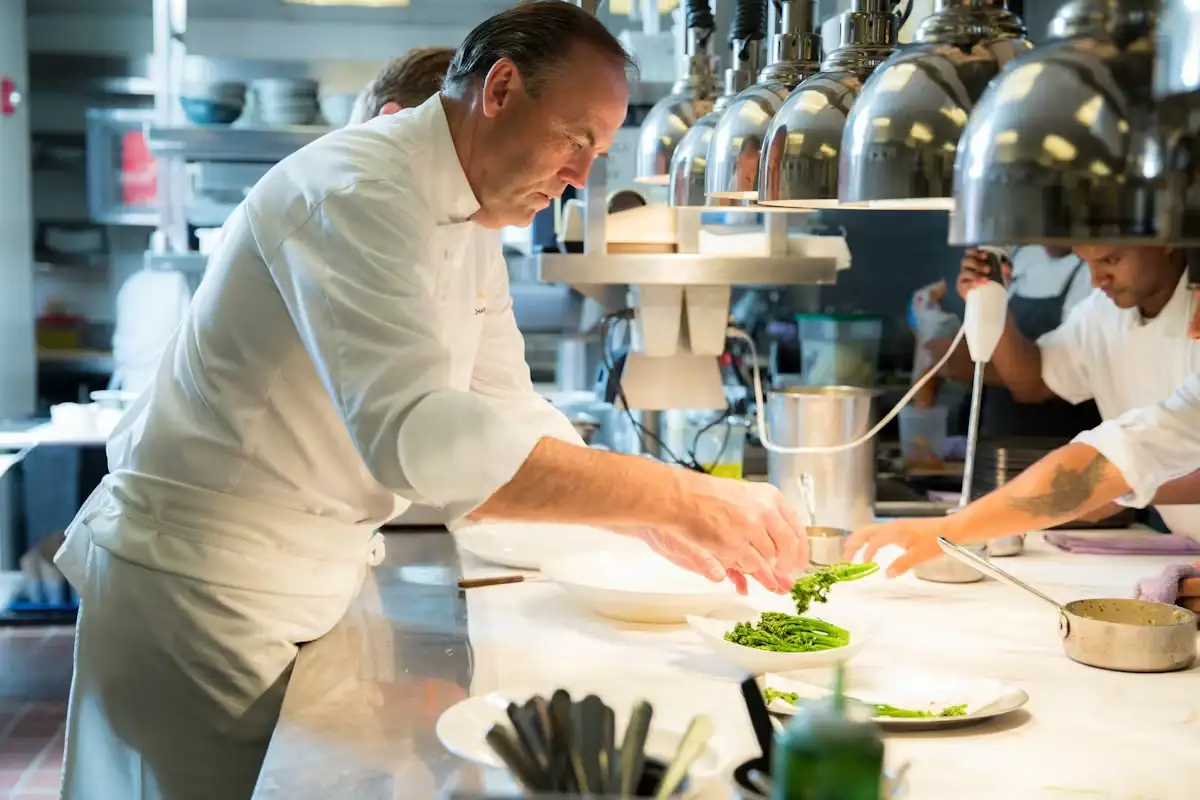 employees standing around a table in a restuarant listening to a chef